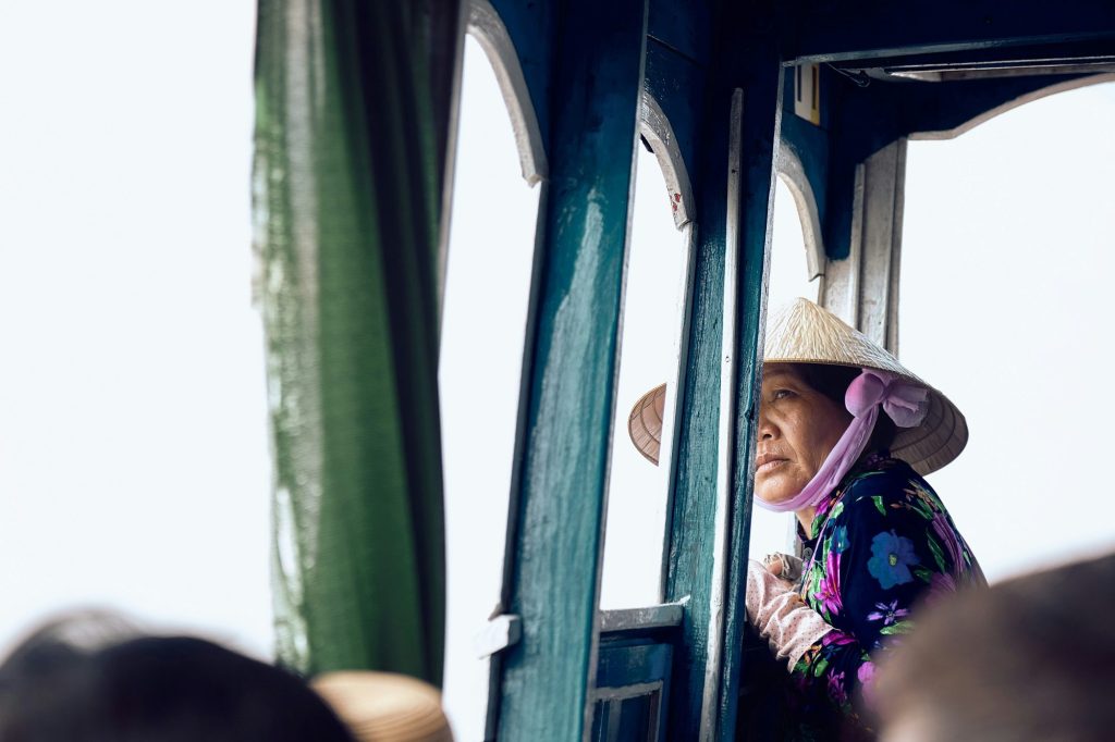 A traveller taking in the Hau River from the bow of a small wooden cruise boat