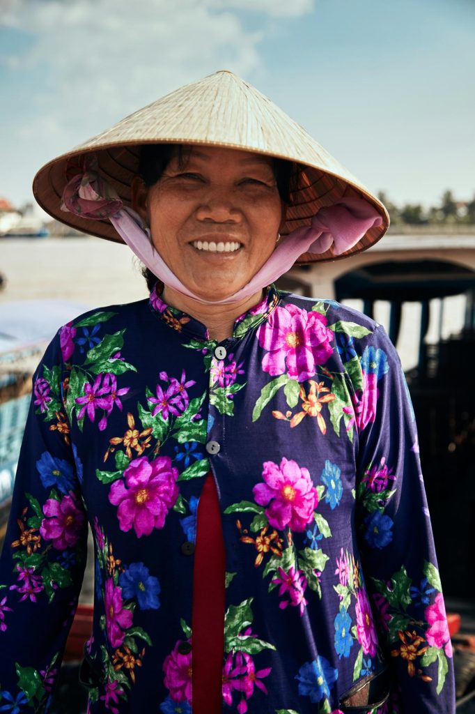 A smiling delta villager in a conical non la hat on the Can Tho back-roads cycling route