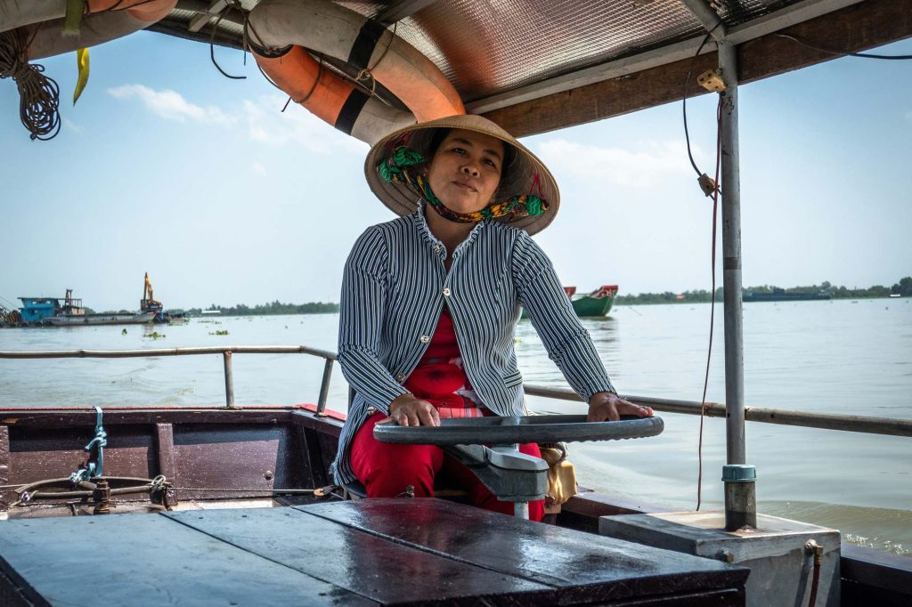 A Hau River boat captain at the helm during an evening cruise, Can Tho