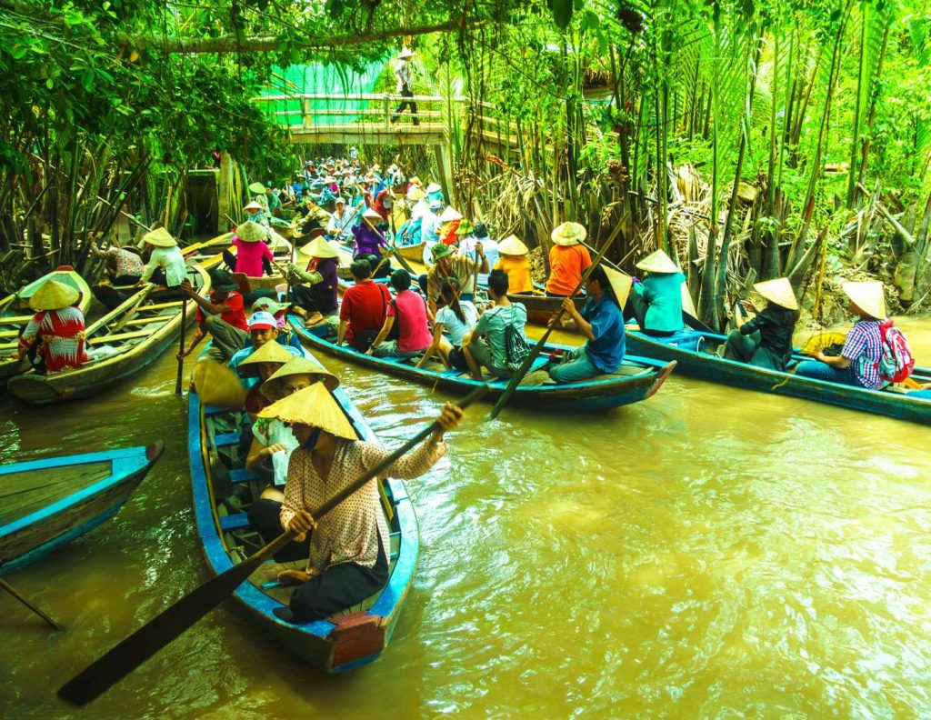 Wooden boats loaded with produce at a Ben Tre canal-side market — the classic delta water scene