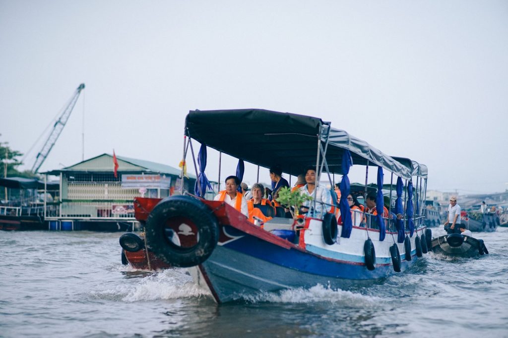 travellers riding a local boat through the market — Cai Rang Floating Market at Dawn, mekongtodo real Mekong Delta tour